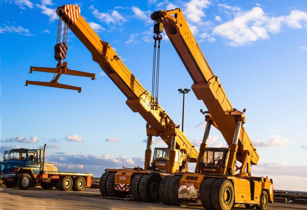 Two mobile cranes with raised booms at an industrial worksite